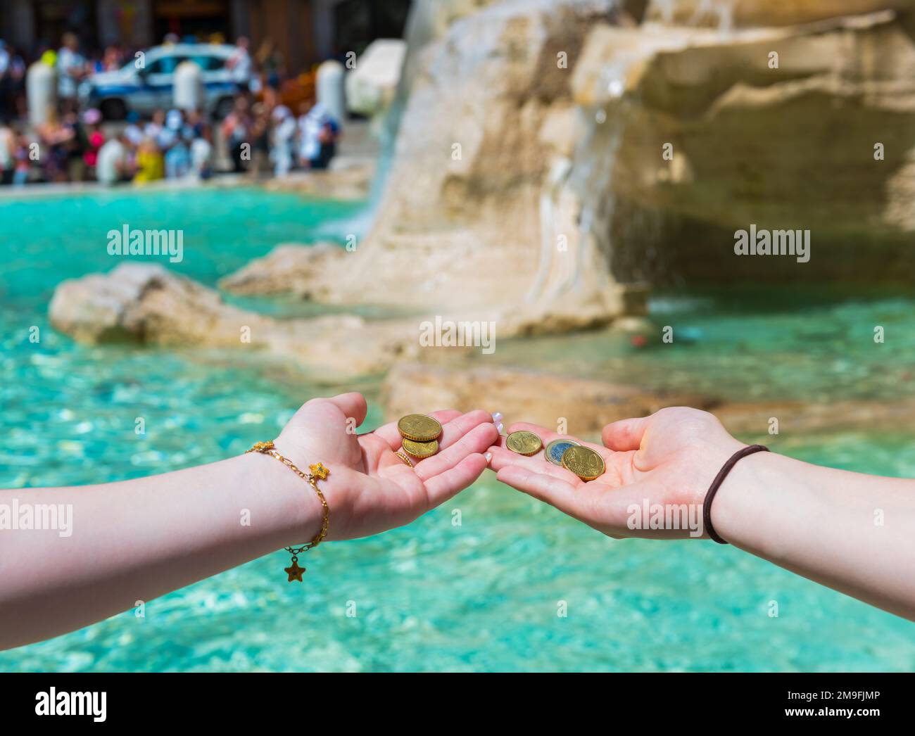 Girls throwing coin at Trevi Fountain for good luck. Hands keeping coin. Trevi Fountain, Rome, Italy. Stock Photo