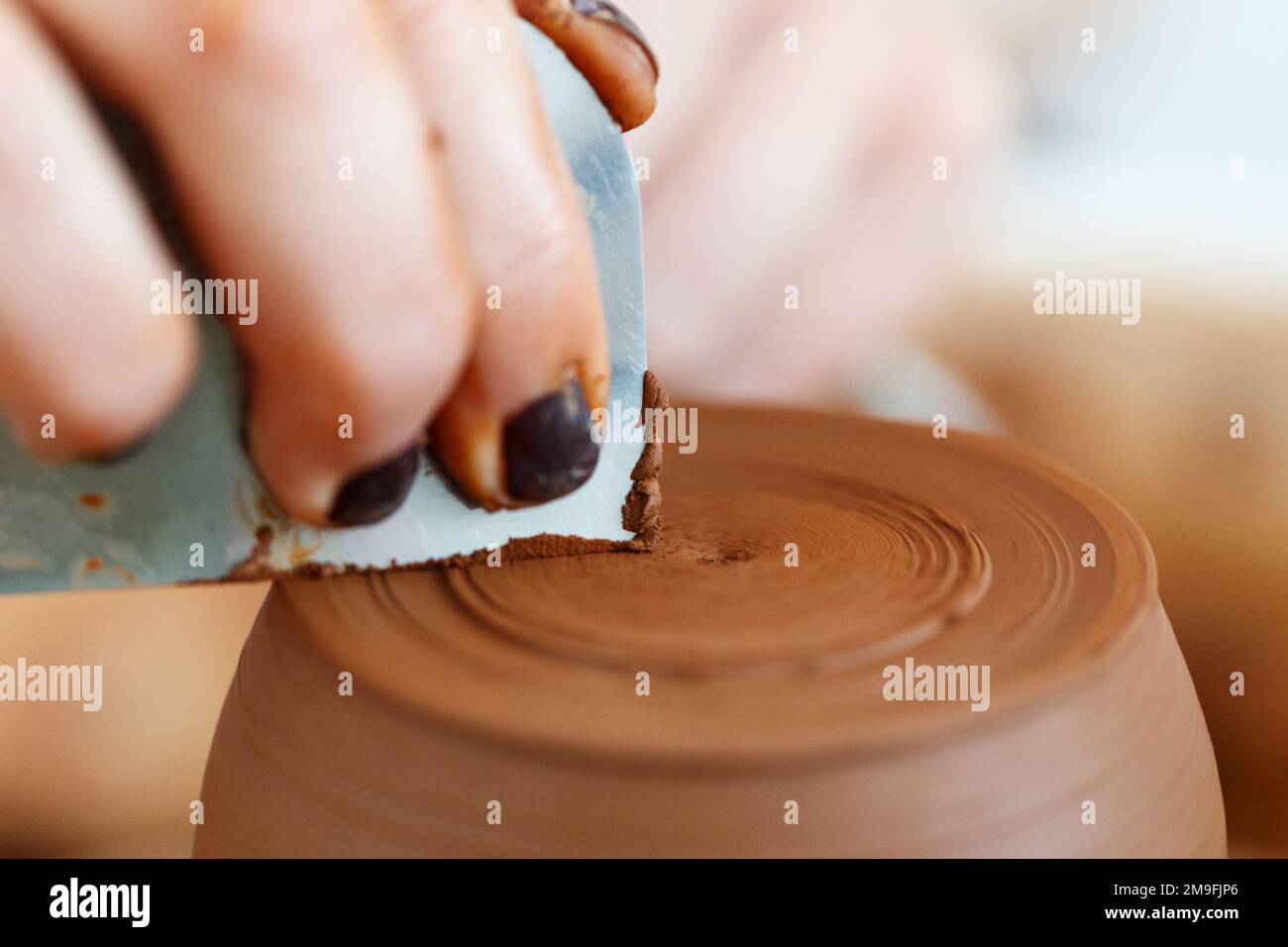 Cropped close up image. Woman's hands molding clay, making a clay pottery in the handicraft workshop. Artisan production earthenware concept. Macro sh Stock Photo
