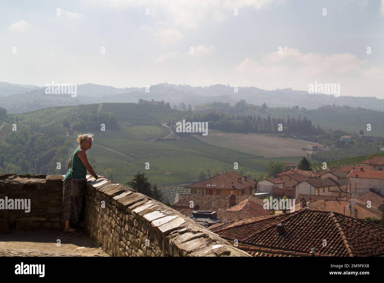 Woman enjoying the beautiful view over the Tuscan countryside from a high point in an old village Stock Photo