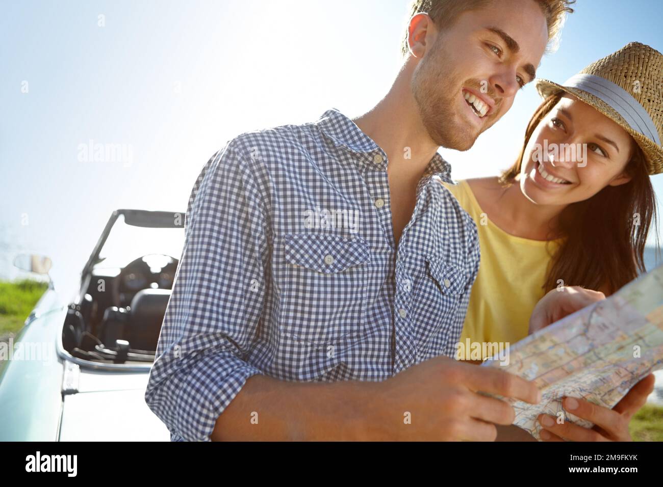 Road trip, travel and couple with map by car on summer holiday, vacation and weekend getaway by ocean. Adventure, freedom and happy man and woman Stock Photo