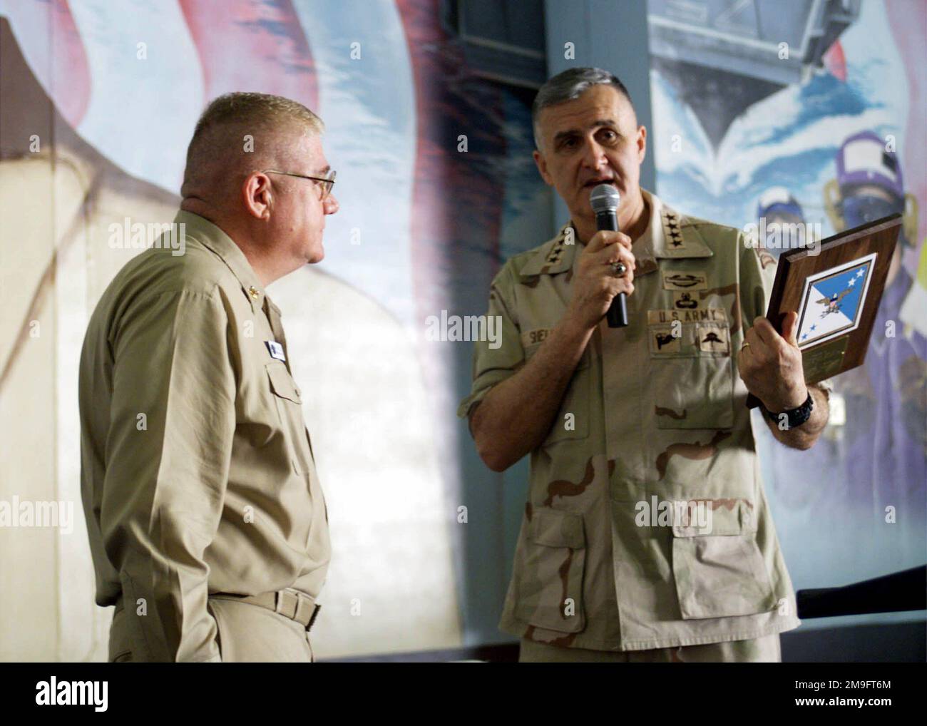 US Army General Henry Shelton, Chairman Joint Chiefs of STAFF, presents a Joint Chiefs of STAFF plaque dedicated to the crew of USS HARRY S. TRUMAN (CVN 75) to US Navy Boiler Technican MASTER CHIEF (Surface Warfare/Air Warfare) Mike Driscoll, Command MASTER CHIEF, while addressing the Sailors and Marines in the ship's hangar bay. Truman is on station in the Persian Gulf in support of Operation SOUTHERN WATCH. Subject Operation/Series: SOUTHERN WATCH Base: USS Harry S. Truman (CVN 75) Stock Photo