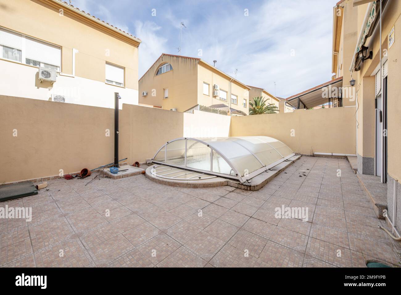 Interior patio of a single-family home with stoneware floors and a pool covered by a folding methacrylate bubble Stock Photo