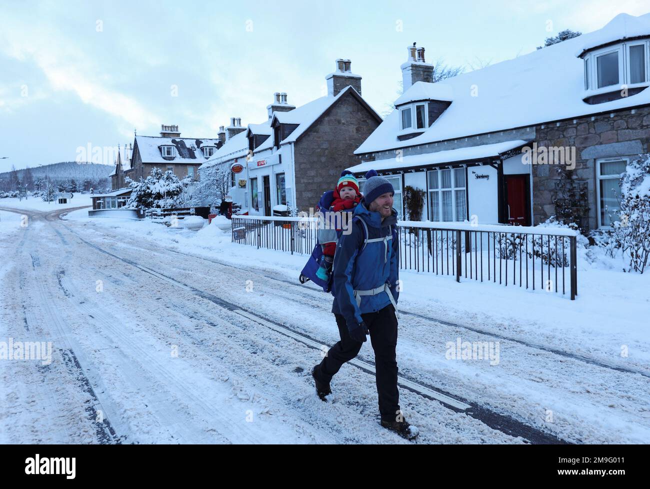 A man carrying a child walks on a road in Carrbridge, Scotland, Britain January 18, 2023. REUTERS/Russell Cheyne Stock Photo