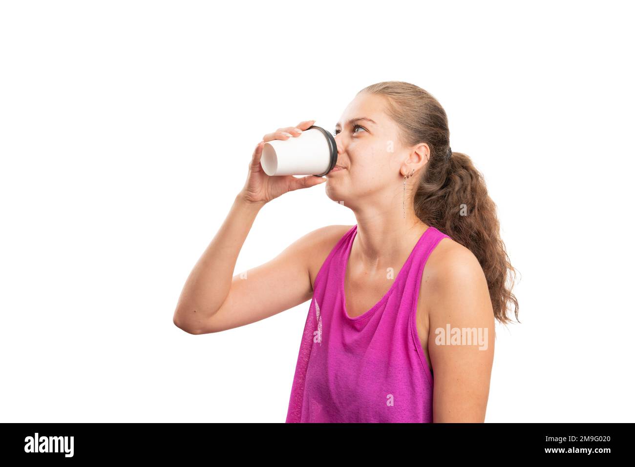 Adult female model wearing gym attire pink tanktop drinking coffee from paper cup as morning gym workout concept with blank copyspace for advertising Stock Photo