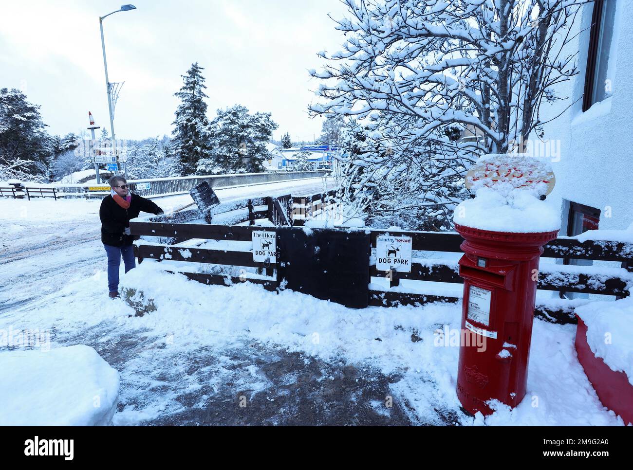 A woman shovels snow in Carrbridge Scotland, Britain January 18, 2023. REUTERS/Russell Cheyne Stock Photo