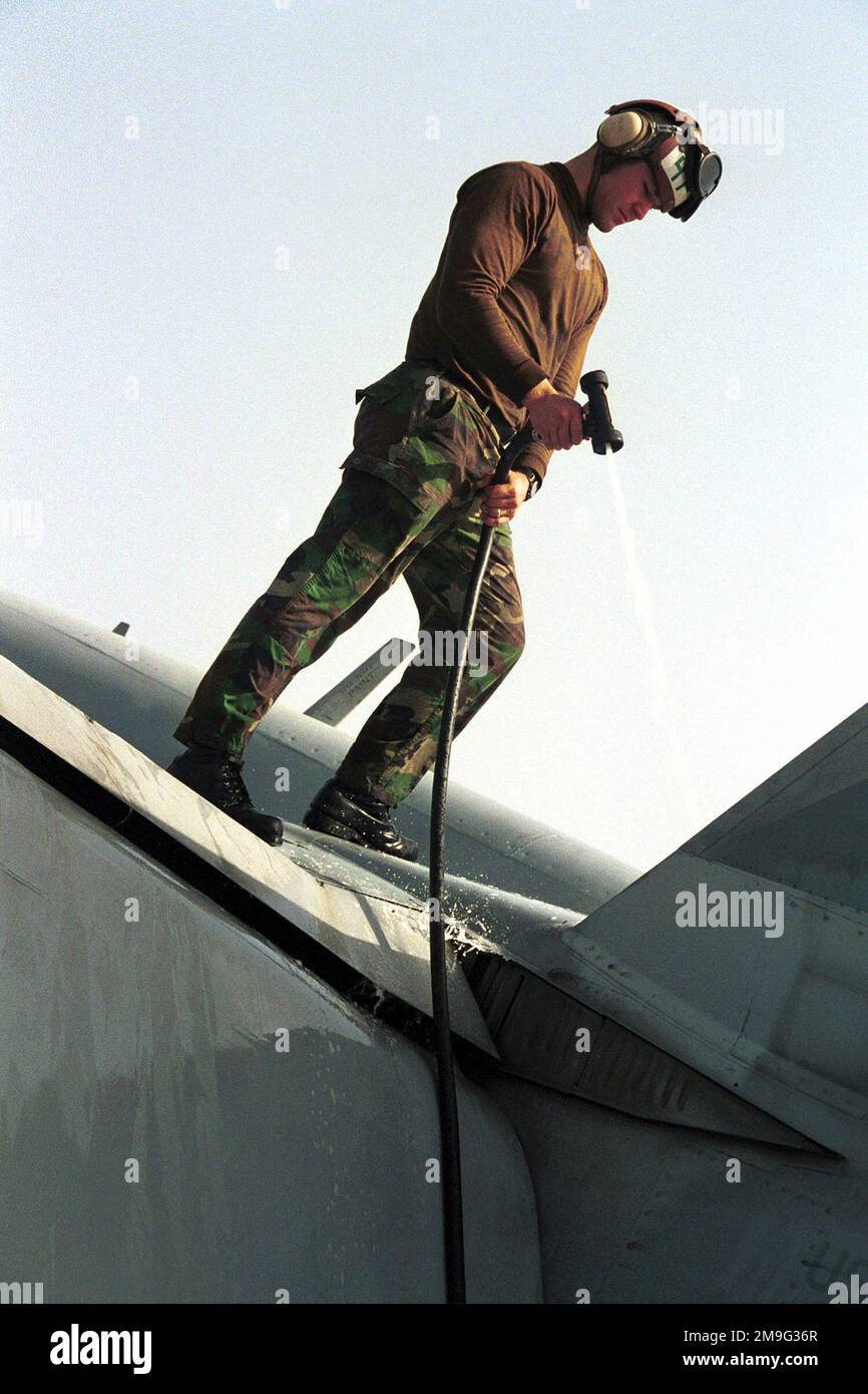 US Navy AIRMAN Apprentice Mike Mullen washes the wing of an F/A18