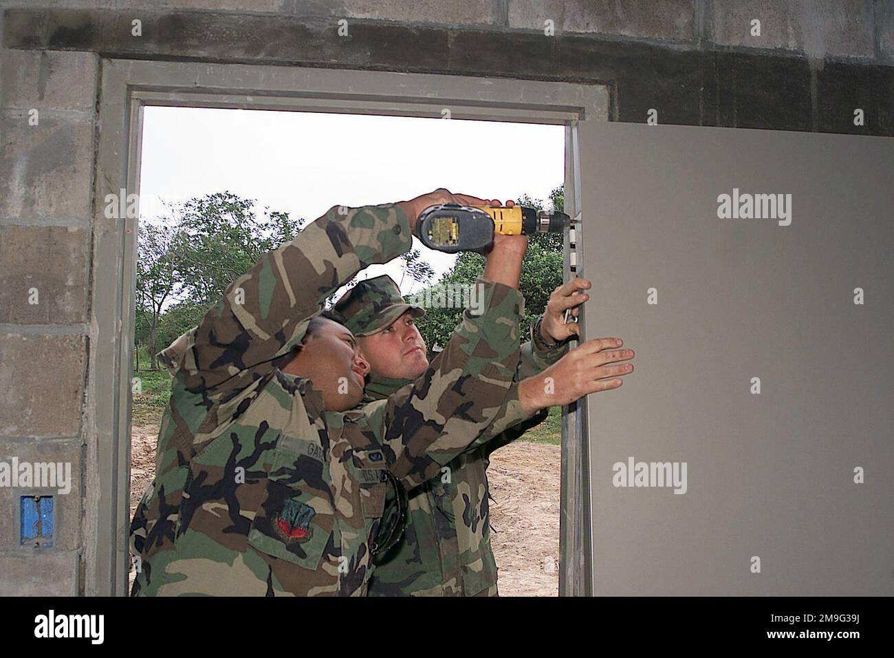 US Air Force Lance Corporal Timothy Merren holds the door while US Air Force AIRMAN First Class Albert Gates secures its hinges for the new school at Las Palmas Paraguay, during Exercise NEW HORIZONS. Combined Task Force Guarani Springs conducts engineering and medical operations in Paraguay, enabling joint training. The task force will renovate, construct and improve the infrastructure of four schools, four water wells, two medical clinics, and conduct mutable Medical Readiness Training Exercises (MEDRETES), and Veterinarian Readiness Training Exercises (VETRETES) as agreed to by the governme Stock Photo