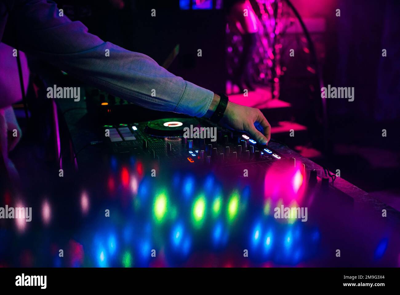 hands DJ mixing and playing music on a professional controller mixer in a Stock Photo