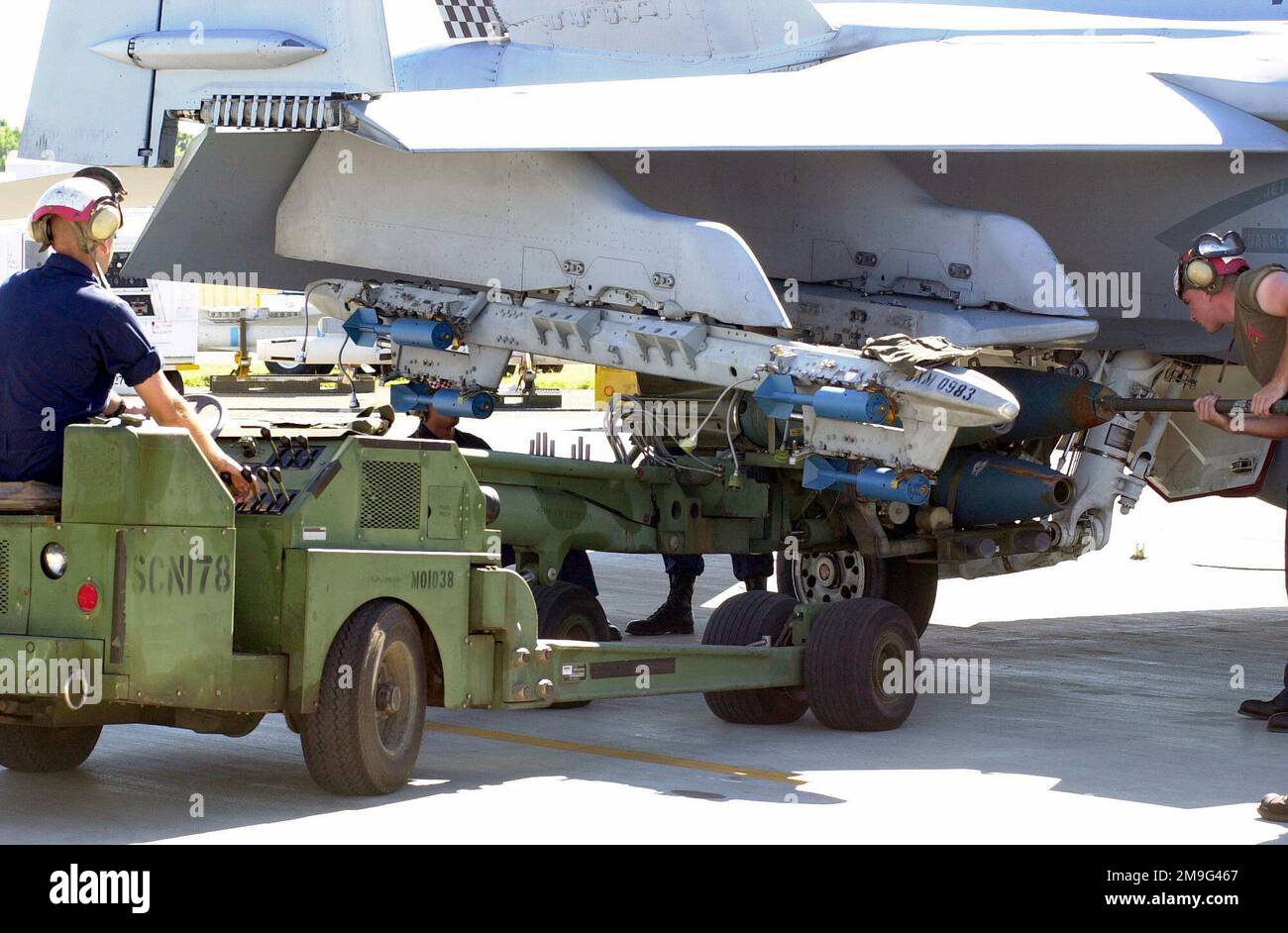 010507-F-2022C-004. [Complete] Scene Caption: Private First Class Samual Gregorey, USMC, drives the MHU-83 C/E Munitions Loading System. Other members from the 533rd Marine Strike Fighter Squadron (VMFA) prepare to load three 305 pound Mk 81 practice bombs with Mk 15 bomb retarding fins attached, onto the F/A-18D Hornet during Exercise TANDEM THRUST. The F-18 is also carrying six BDU-48/B 10-pound practice bombs on the A/A37B-6E Multiple Ejector Rack. TANDEM THRUST is a combined US, Australian, and Canadian military training exercise. This biannual exercise is being held in the vicinity of Sho Stock Photo