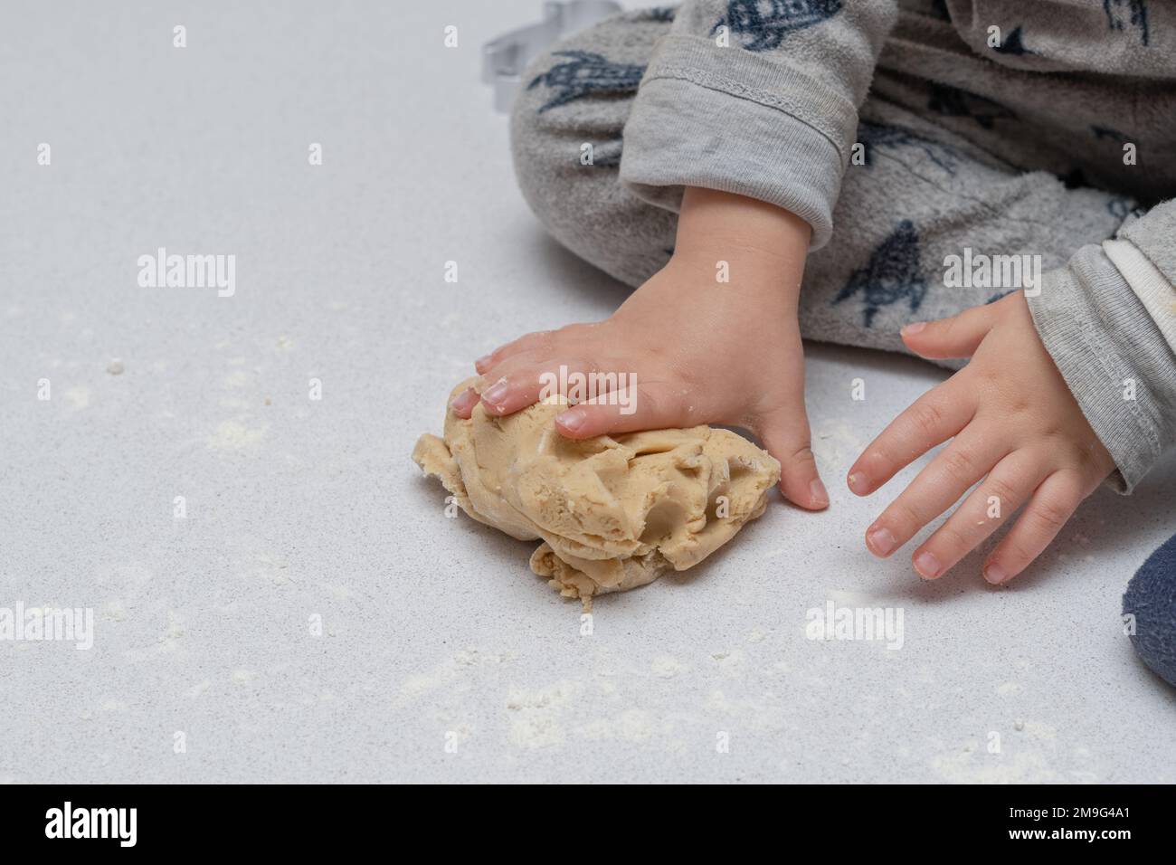 close-up of unrecognizable child's hands kneading dough to make cookies ...