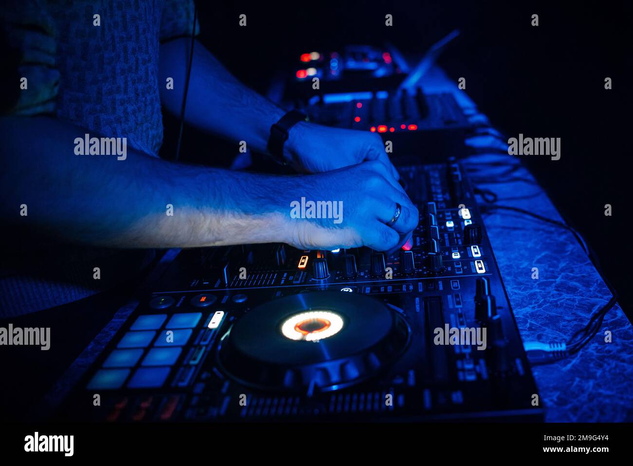 hands DJ mixing and playing music on a professional controller mixer