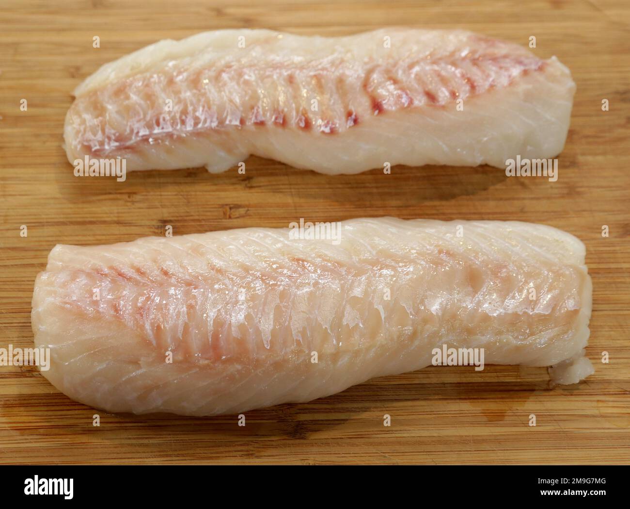 Raw fresh cod fillets on a board. Stock Photo