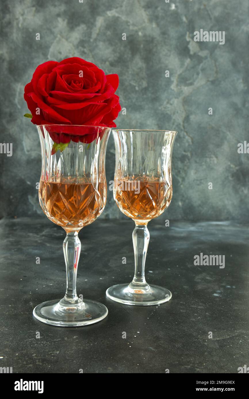 Close up two glasses of liquor and a rose on a black background. Stock Photo