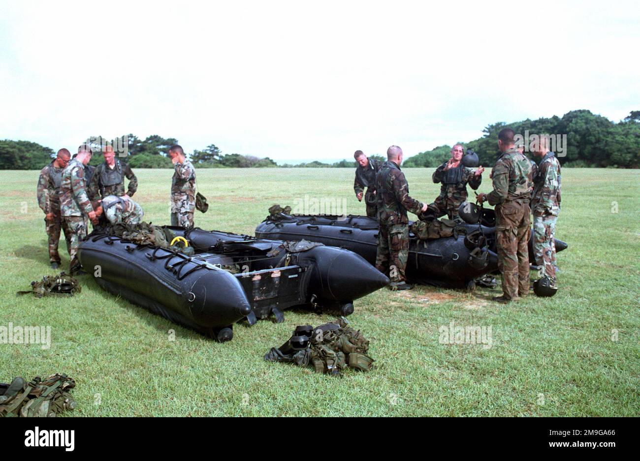 The Marines of Third Reconnaissance Battalion (3D RECON), 3D Marine Division, Okinawa, Japan, look over their gear before a helecopter reaches the landing zone (LZ), where it will be loaded with the Combat Rubber Reconnaissance Craft (CRRC) and a team of Marines during helo-cast training. Base: Camp Schwab Country: Japan (JPN) Scene Major Command Shown: 3rd Recon BN Stock Photo