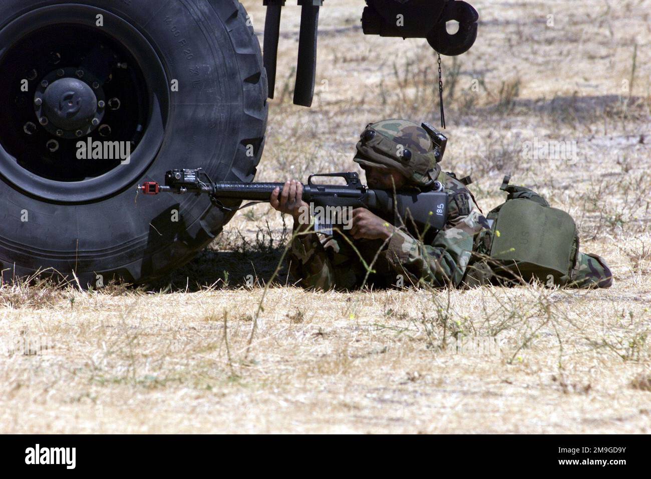 A soldier takes cover when oppostion forces storm the entry control point during Operation GOLDEN MEDIC 2001. Reserve forces from all over the nation are participating in Golden Medic, a multi-unit, medical, field training exercise held at Parks Reserve Forces Training Area, Dublin, California, in which the Army transports simulated casualties from the frontline through various staging areas to a main tent in order to train personnel in medical procedures and evacuation methods. Attached to the helmet, upper body and M-16A2 rifle is the Multiple Integrated Laser Engagement System (MILES) gear Stock Photo