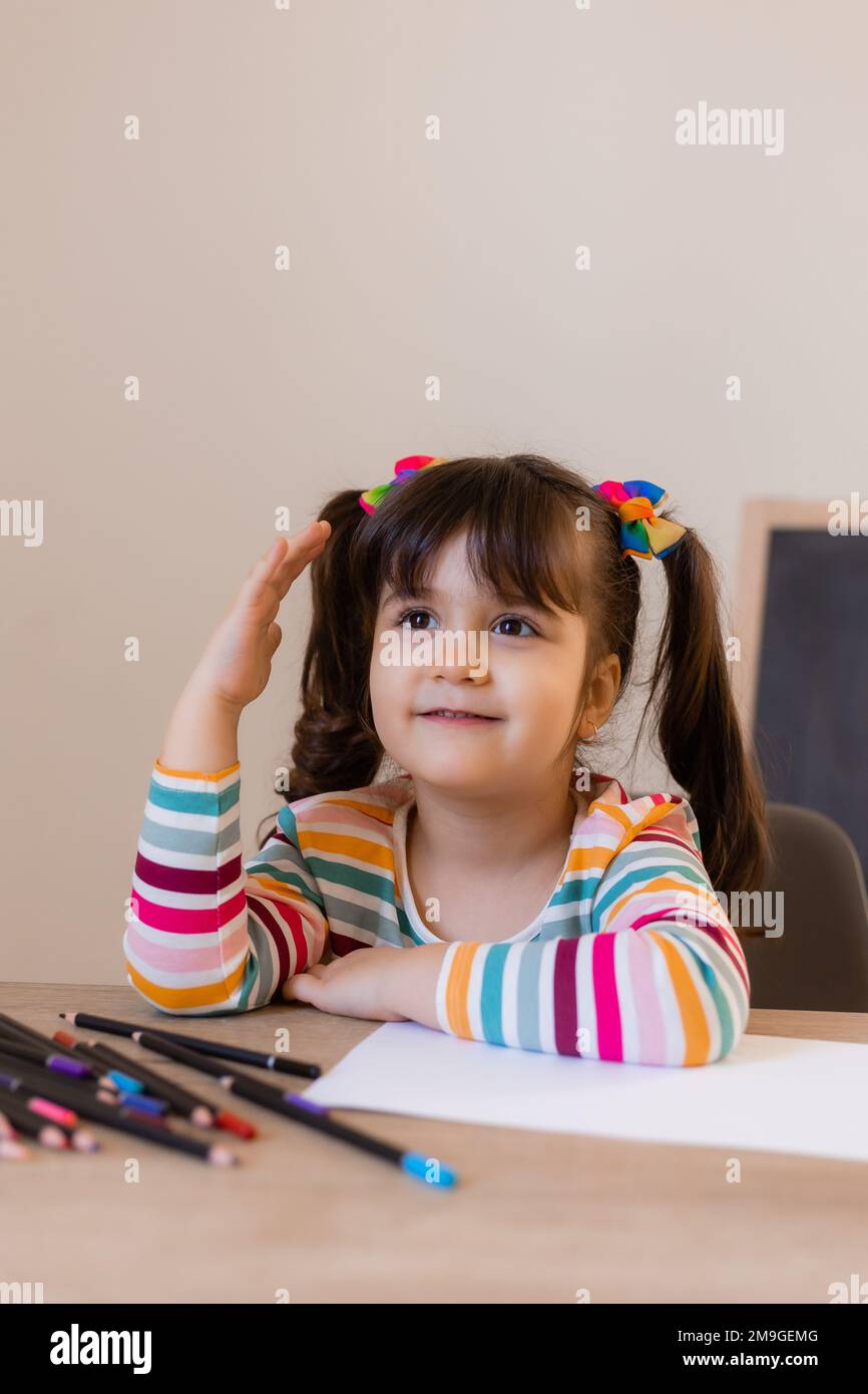 a happy cute little girl in a drawing lesson raises her hand at the top Stock Photo