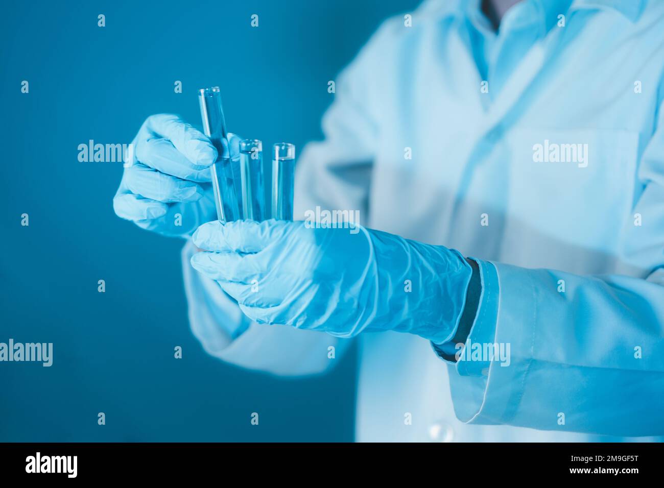 Scientist hand hold test tubes filled with blue sample chemicals in