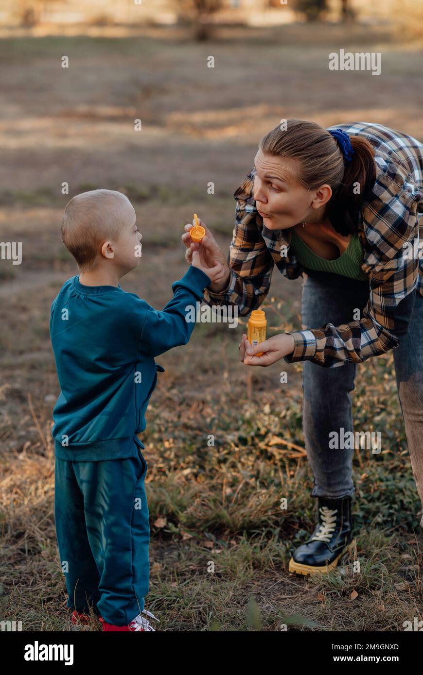A boy, person with down syndrome walks in the park with his mother