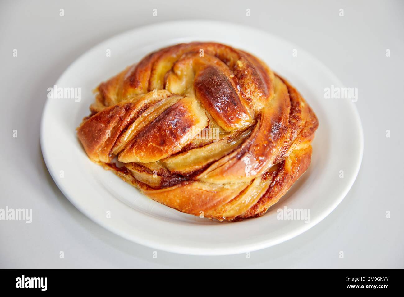 Danish cinnamon bun on a white plate Stock Photo