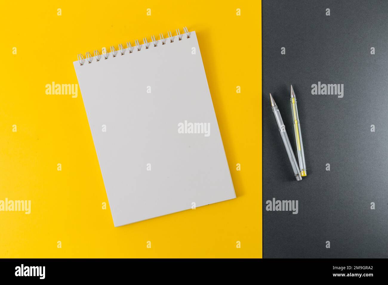 Yellow and gray gel pens with a notepad on a yellow and gray background. Stock Photo