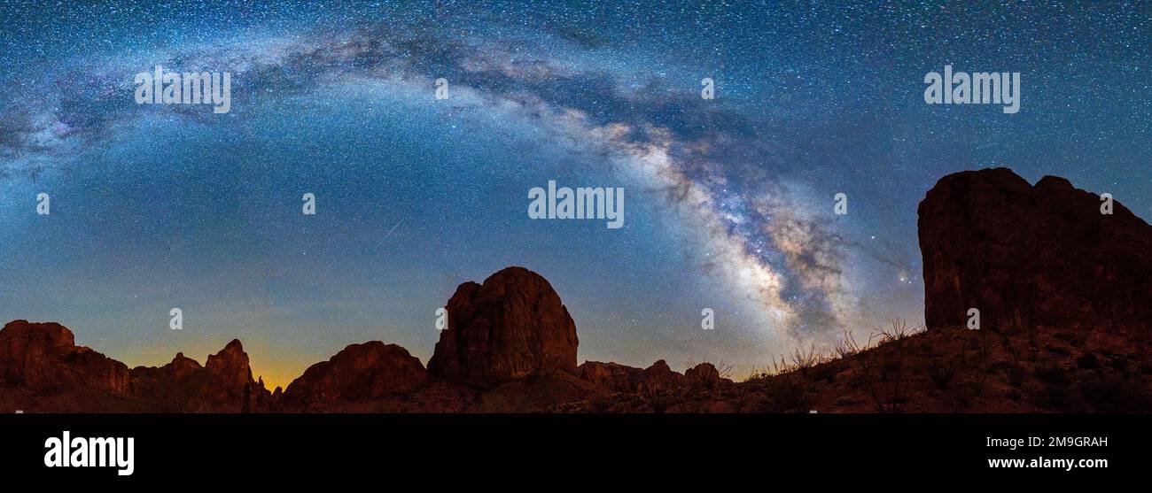 Landscape with rock formations in desert under Milky Way galaxy in sky at night, Kofa Queen Canyon, Kofa National Wildlife Refuge, Arizona, USA Stock Photo