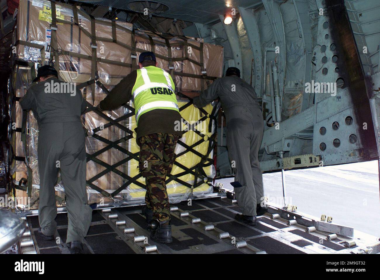 Aerial port personnel and loadmasters push a pallet off the ramp into