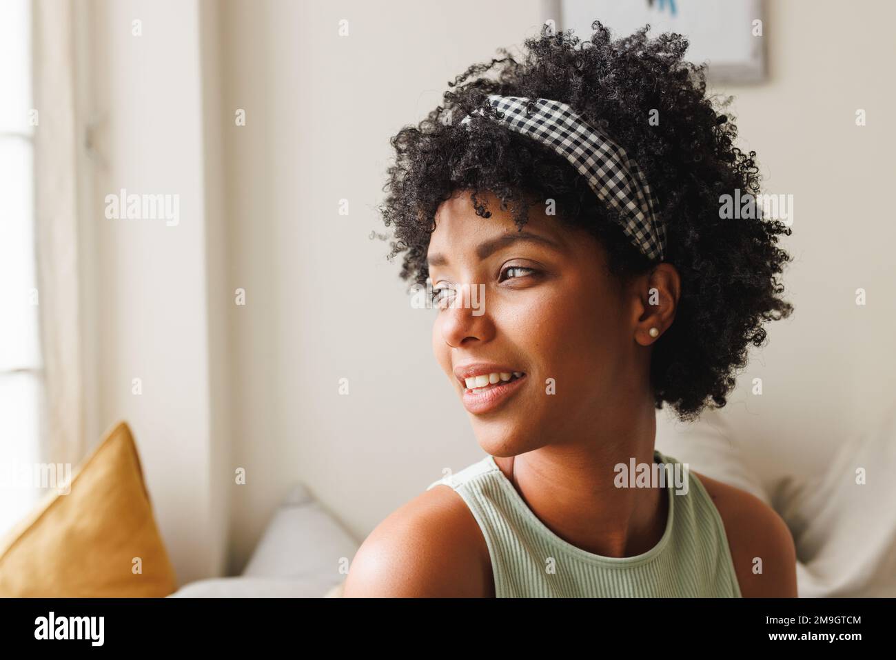 Close-up of thoughtful biracial young woman with afro hair looking away against white wall at home Stock Photo