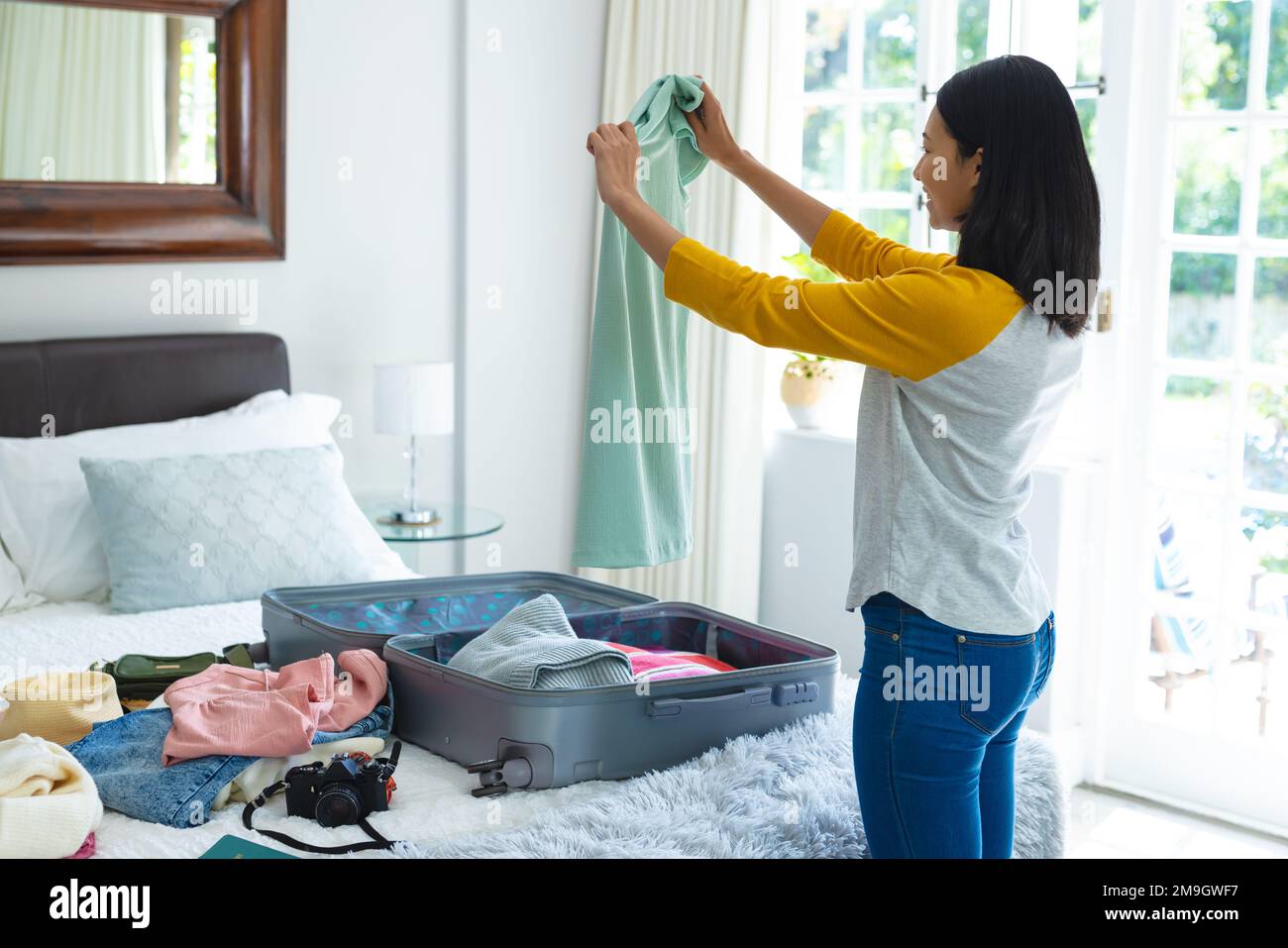 Latina Young Woman Packing Luggage For Holidays In Her Bedroom