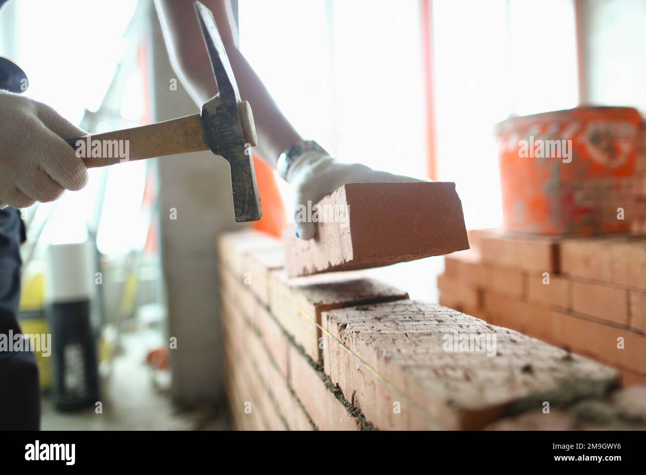 Industrial worker builds interior walls using hammer and level to place