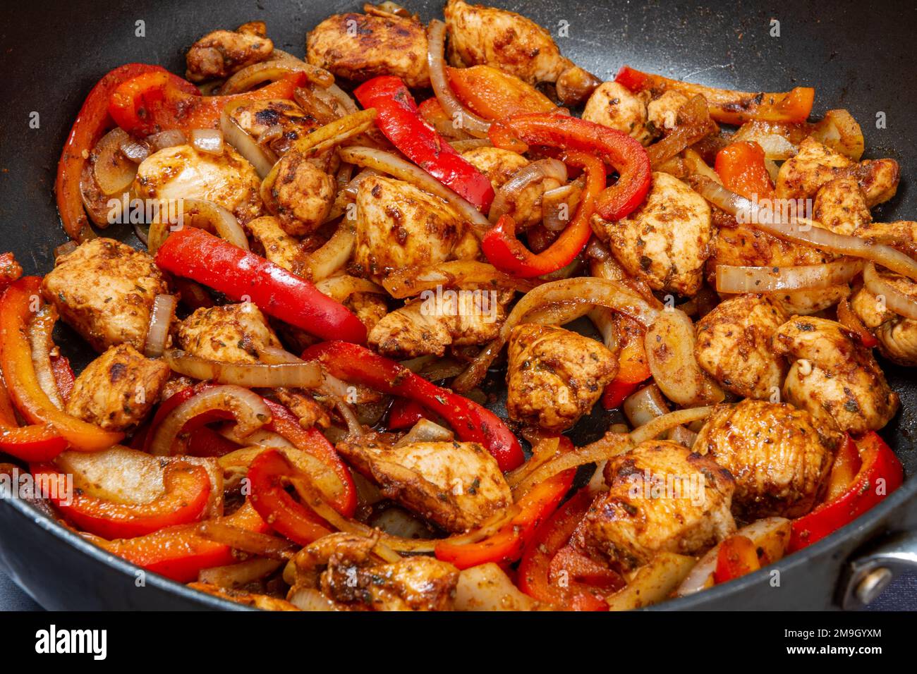 Chicken red pepper and onion with fajita seasoning in pan Stock Photo Alamy