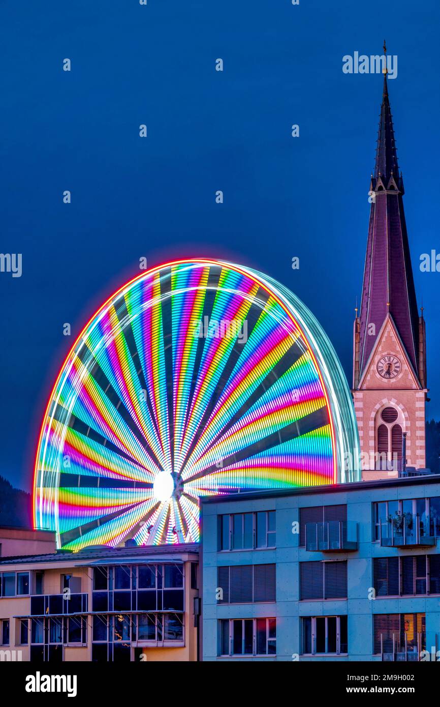 View of the ferris wheel and the bell tower of the Nikolaikirche; Villach, Austria Stock Photo
