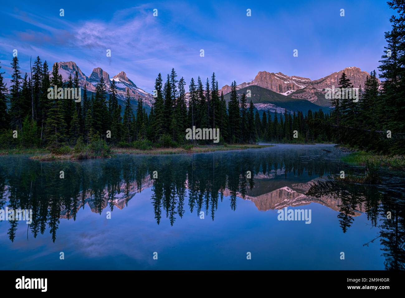 Landscape with Three Sisters Mountains, Mount Lawrence Grassi and lake at sunset, Alberta, Canada Stock Photo