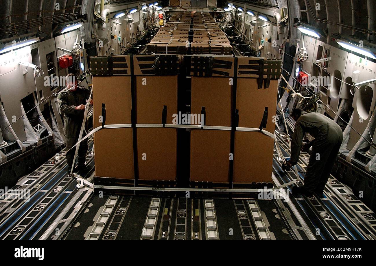 DF-SD-03-17239. [Complete] Scene Caption: US Air Force C-17A Globemaster III loadmasters inspect the Tri-Wall Aerial Delivery System (TRIADS) loaded with Humanitarian Daily Rations (HDR) enroute to the drop zone. Air Force C-17's delivered Humanitarian Daily Rations (HDR) in support of Operation ENDURING FREEDOM from Germany to Afghan refugees who massed inside the borders of Afghanistan. The C-17's carried more than 35,000 HDRs packed in 84 TRIAD boxes. Each box measures 80 inches tall and 48 inches square, containing 420 HDRs. The HDRs were delivered in a first of its kind, high-altitude air Stock Photo