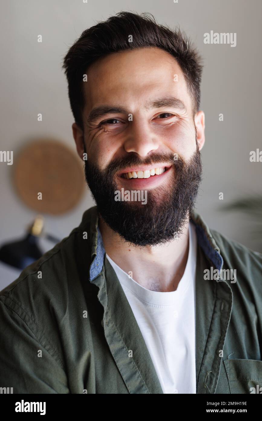 Close-up portrait of bearded biracial handsome young man smiling against white wall, copy space Stock Photo