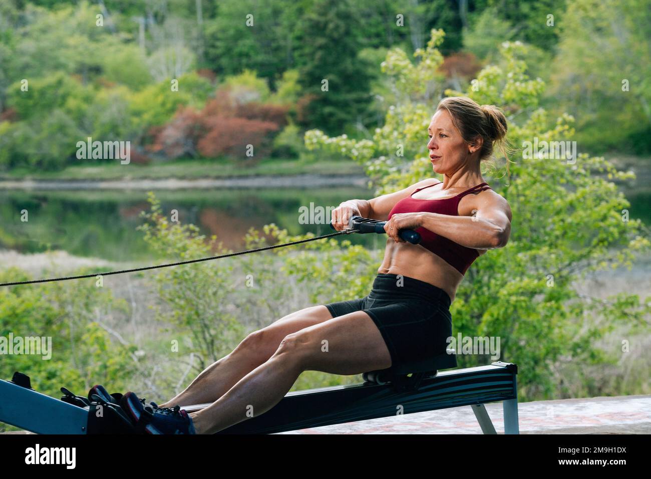 Woman exercising on rowing machine outdoors, Bainbridge Island, Washington, USA Stock Photo