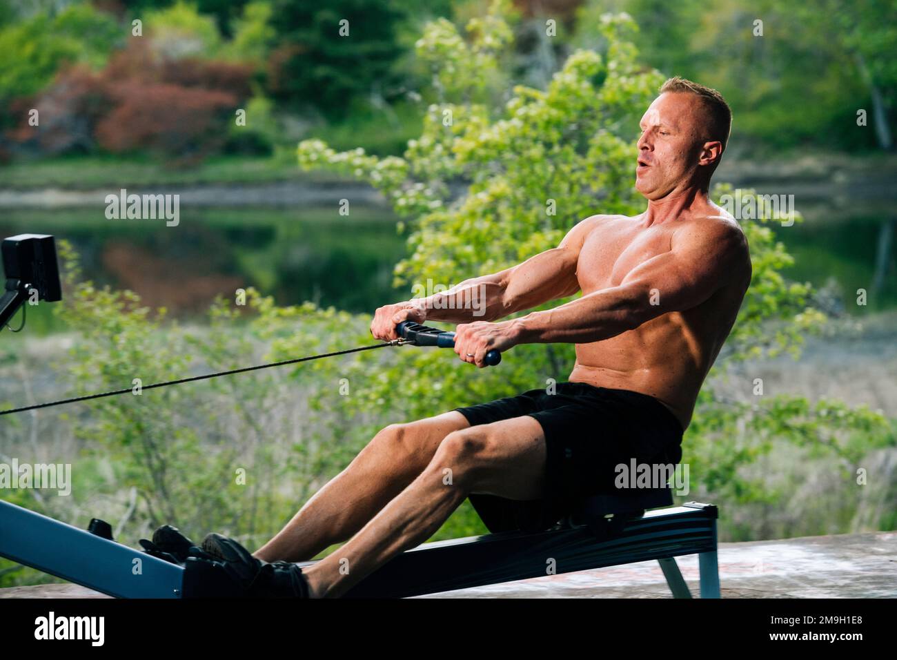 Man exercising on rowing machine outdoors, Bainbridge Island, Washington, USA Stock Photo