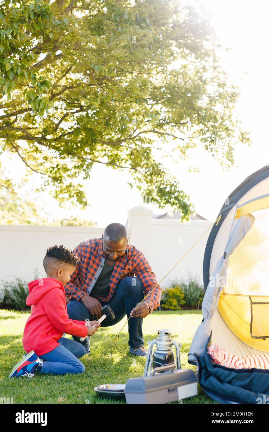 Happy african american father and son pitching tent in their backyard Stock Photo