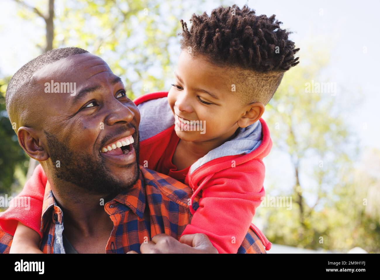 Happy african american father and son embracing and smiling in their ...