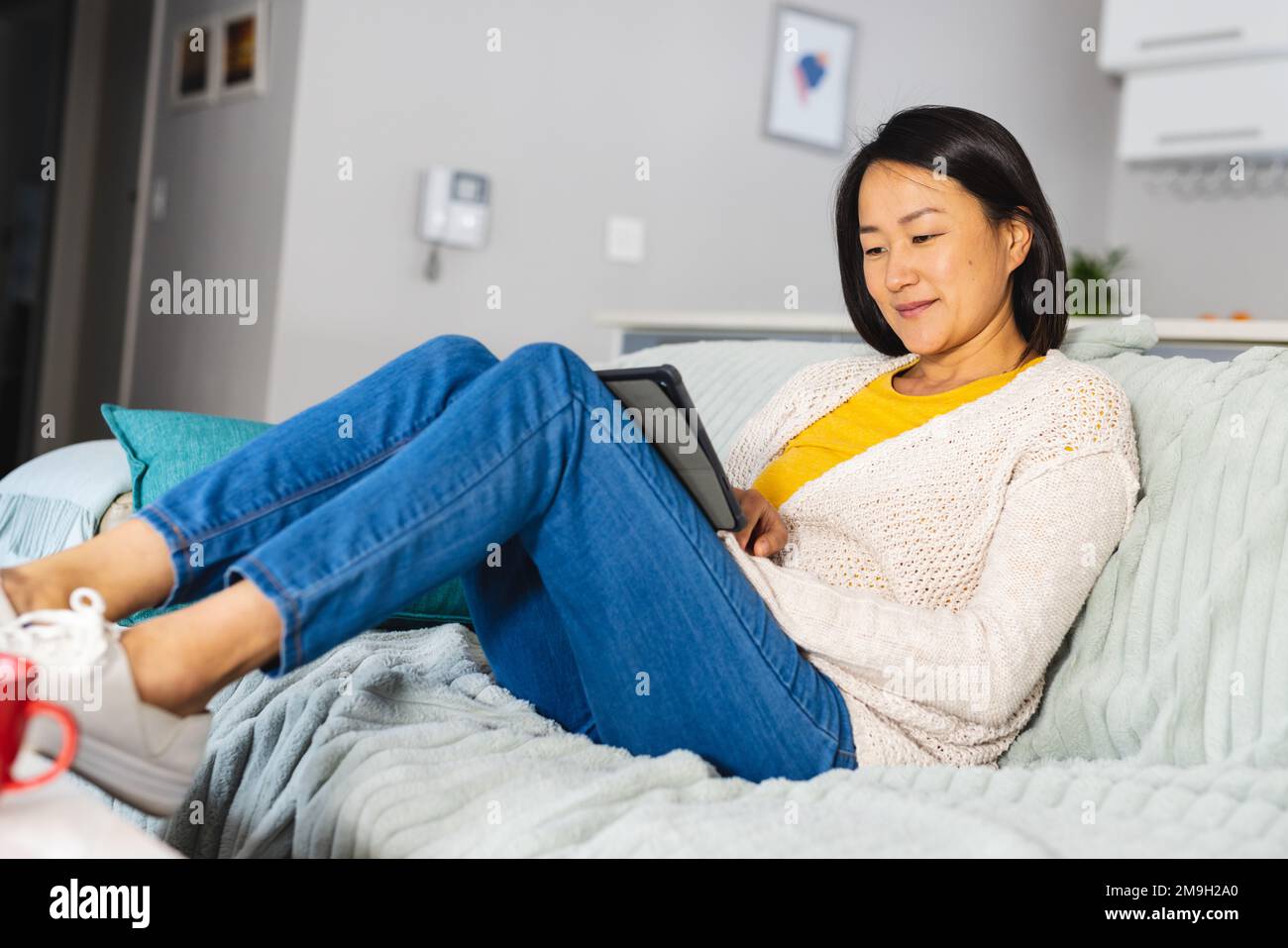Happy asian woman sitting on sofa in living room and using tablet Stock ...