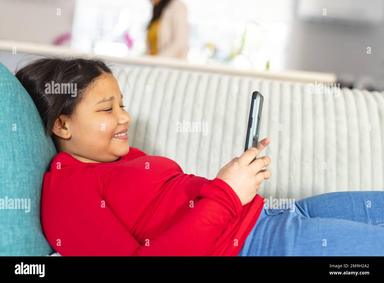 Happy asian girl sitting on sofa in living room and using smartphone ...