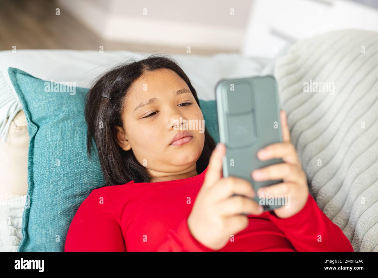 Happy asian girl sitting on sofa in living room and using smartphone ...