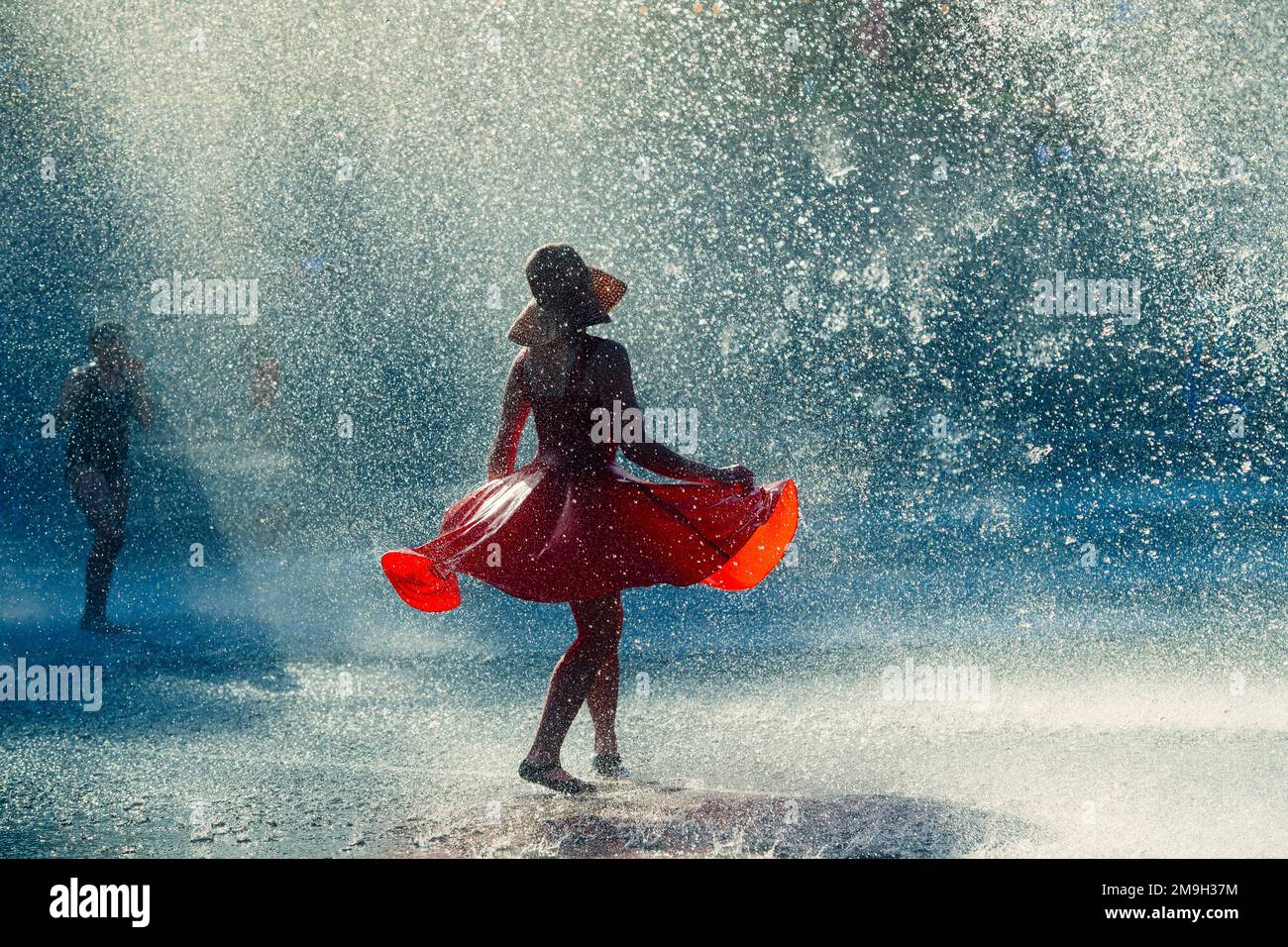 Woman in red dress dancing in fountain, International Fountain, Seattle, Washington State, USA Stock Photo