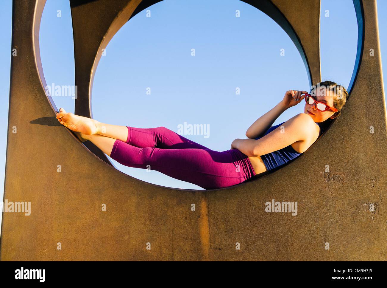 Woman in sunglasses lying on circular structure and looking at camera, Seattle, Washington State, USA Stock Photo