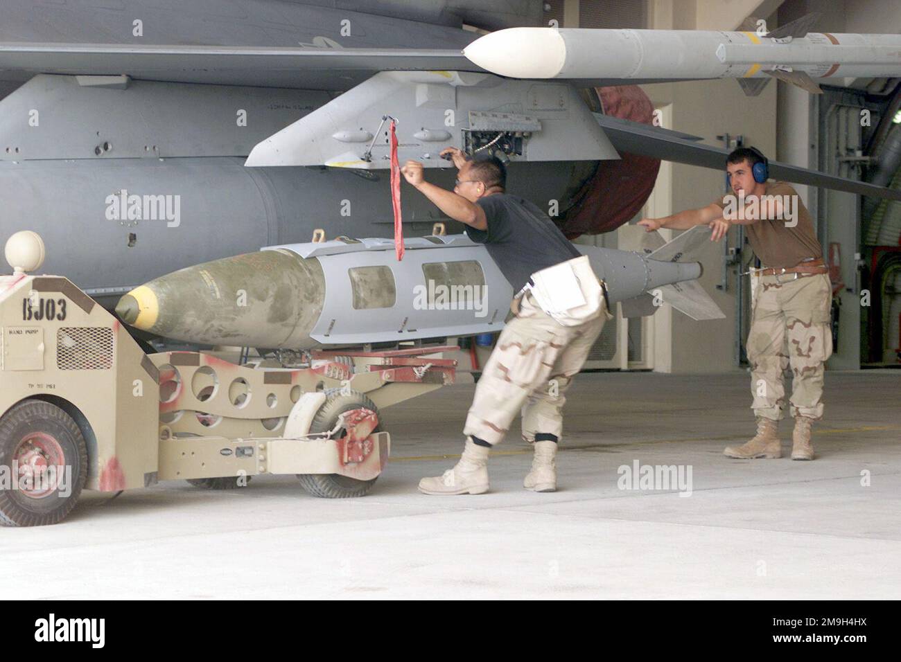 A Munitions SPECIALIST (MS), STAFF Sergeant (SSGT) Blechinger 'Krin' Kriangsak (left) and AIRMAN First Class (A1C) Christopher Caruso, load a Mark-84 bomb onto the weapons rack of an F-16 Fighting Falcon assigned to the 366 Air Expeditionary Group (AEG), deployed in support of Operation ENDURING FREEDOM. Subject Operation/Series: ENDURING FREEDOM Country: Unknown Scene Major Command Shown: CENTCOM Stock Photo