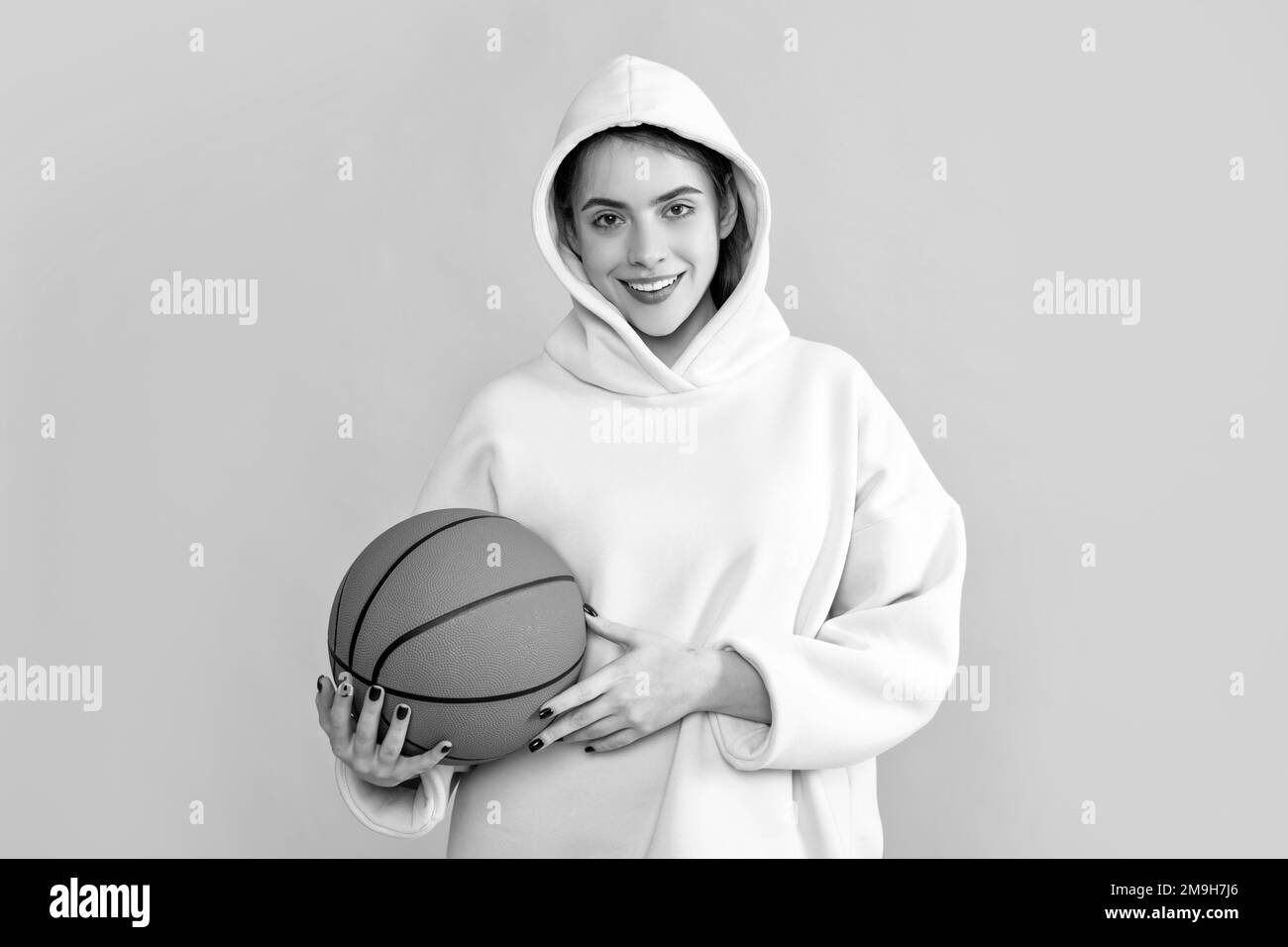 positive sporty girl with basketball ball on yellow background Stock