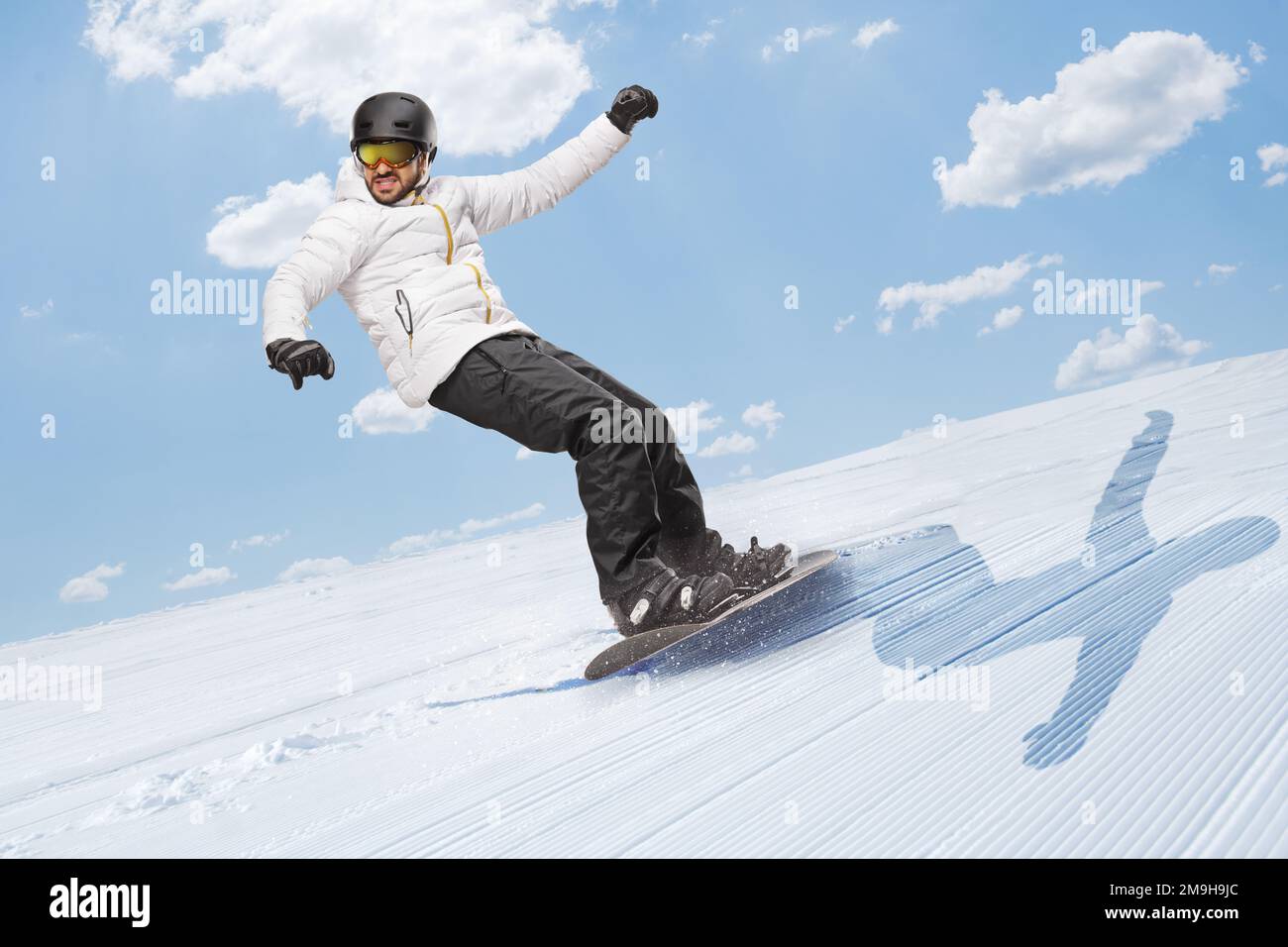 Full length shot of a man gliding with a snowboard downhill on a sunny day Stock Photo