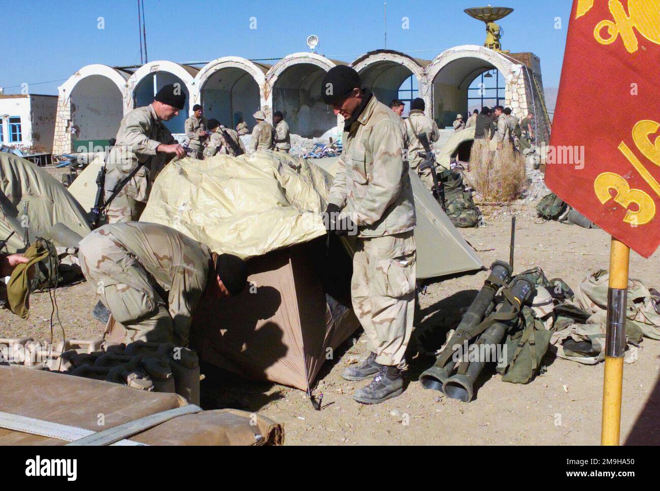 With a couple of M136 LAWs (Light Anti-armor Weapon) at their side, Captain Shane Tomko, USMC, (center) Commanding Officer of Kilo Company, Battalion Landing Team 3/6, 26th Marine Expeditionary Unit (Special Operations Capable) (MEU(SOC)) and two other Marines raise a tent at his bivouac site at the Kandahar International Airport, Kandahar, Afghanistan, during OPERATION ENDURING FREEDOM. Subject Operation/Series: ENDURING FREEDOM Base: Kandahar International Airport Country: Afghanistan (AFG) Scene Major Command Shown: 26 MEU Stock Photo