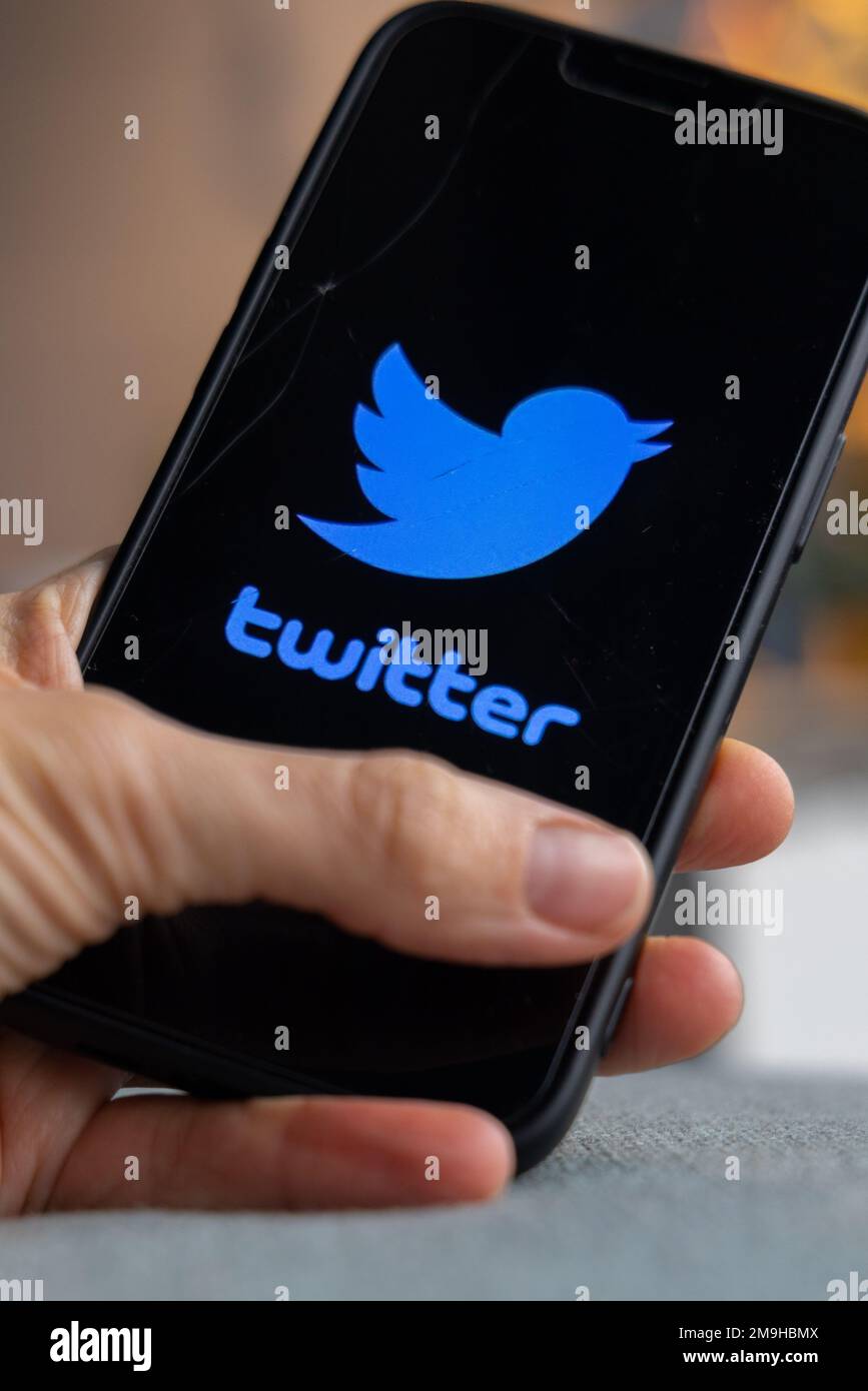 Hand holding a smartphone with Twitter icon on screen. Blue bird and ...