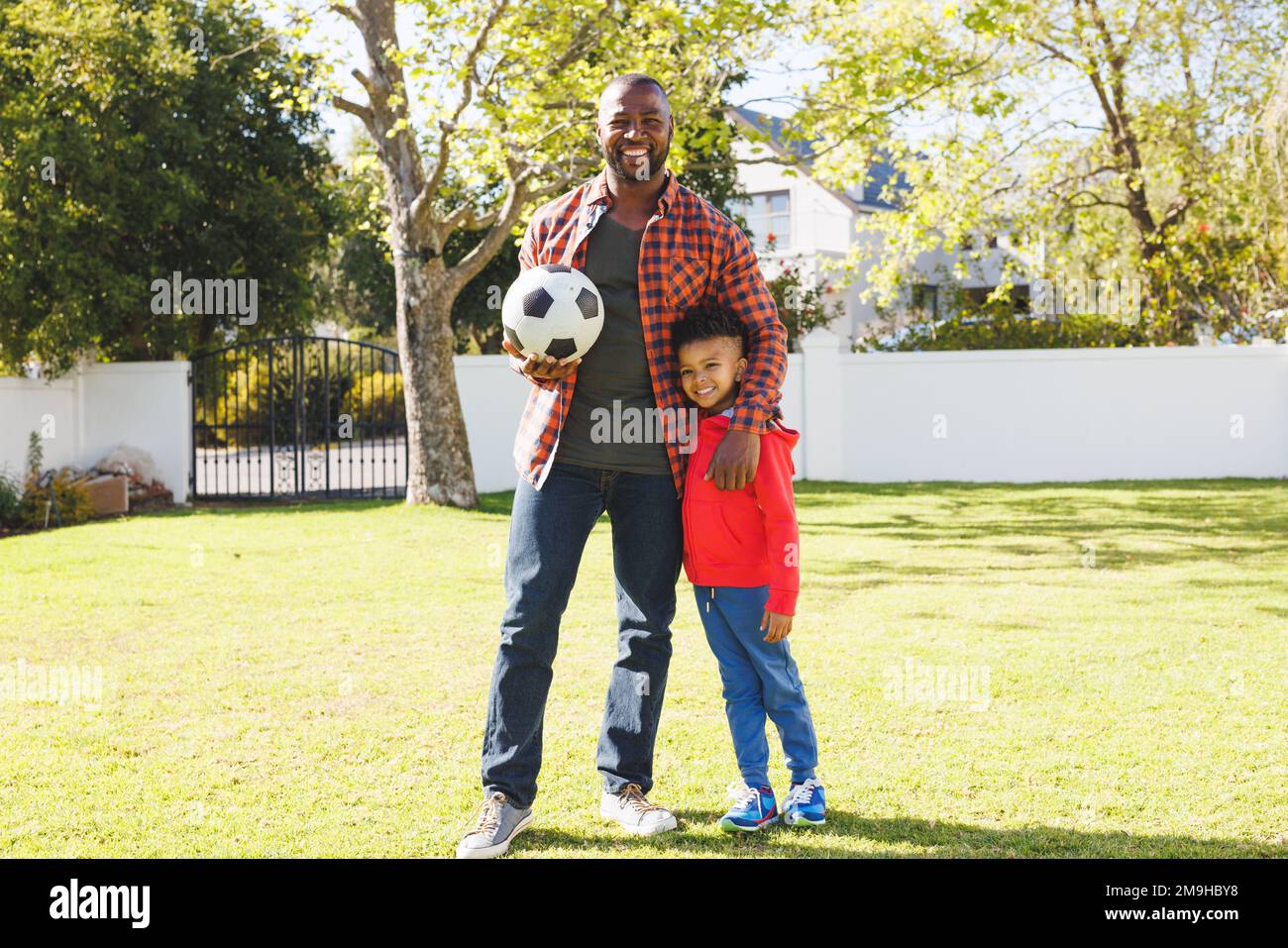 Portrait of happy african american father and son holding football in ...