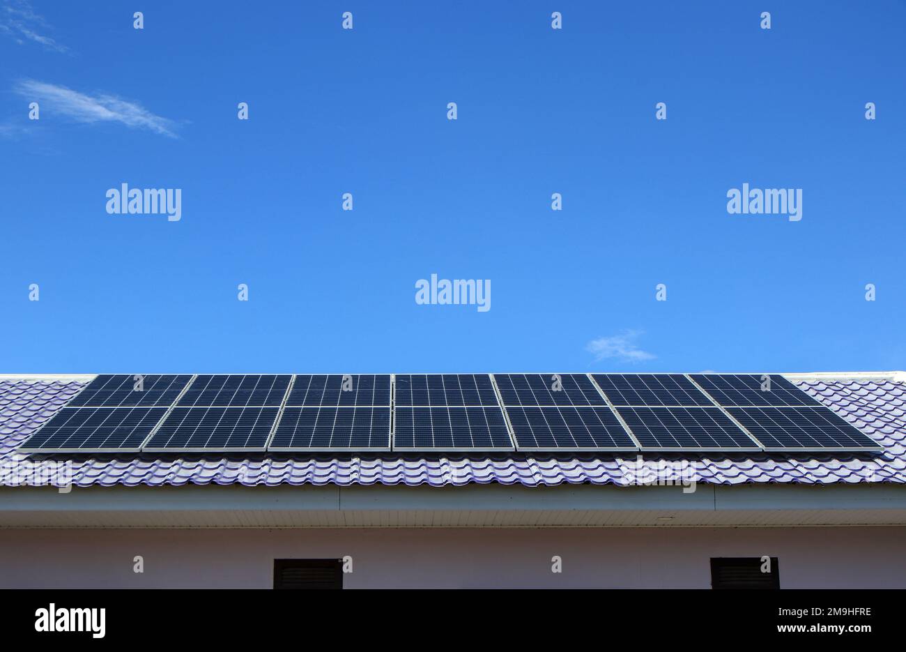 Install new solar panels on the metal sheet roof of the house where electricity is still inaccessible. Stock Photo